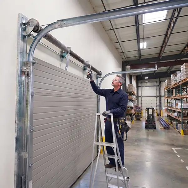 Technician performing maintenance on a commercial garage door in Carrollton TX